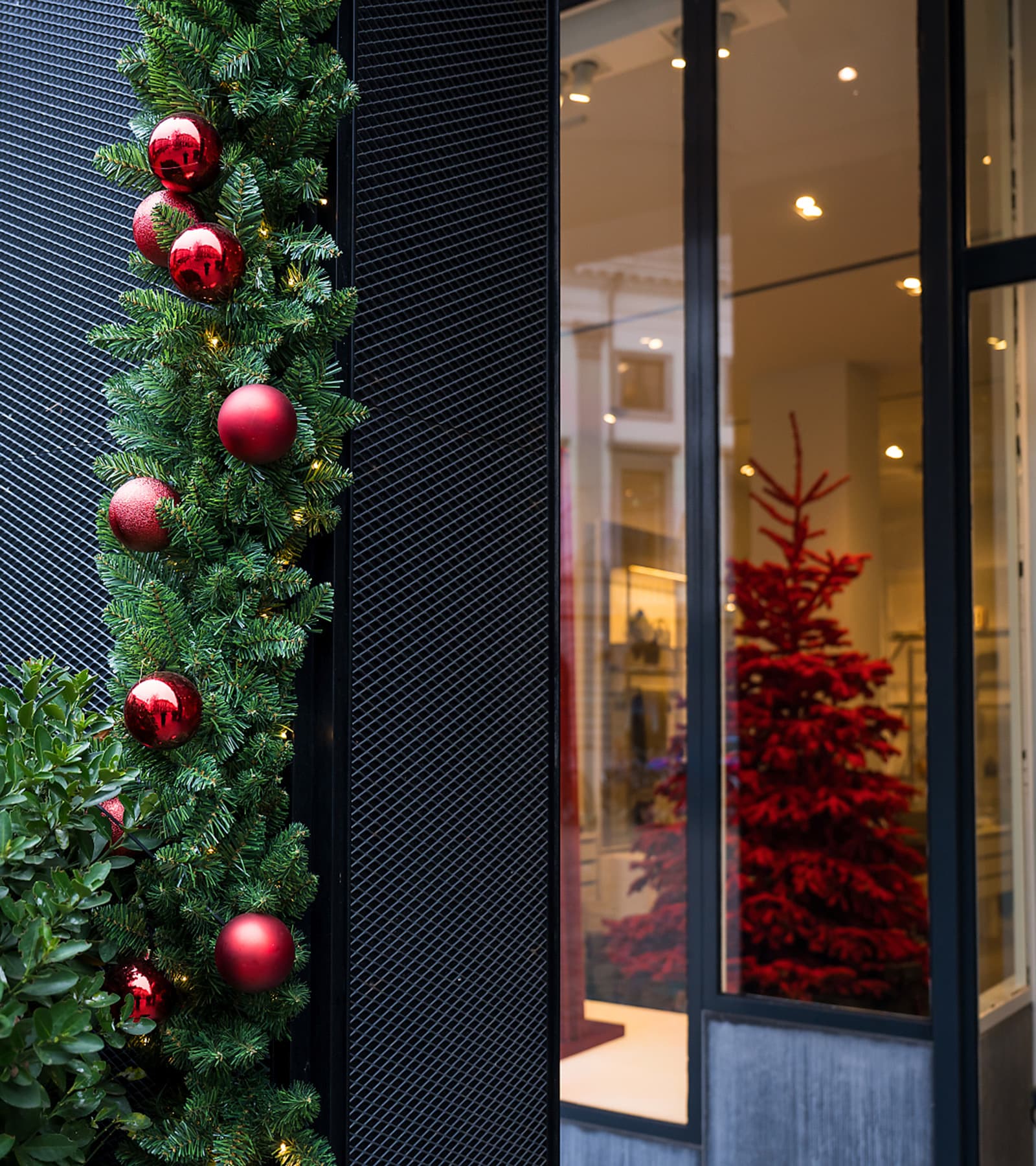 Entrée d’un espace professionnel décorée d’une guirlande de Noël et de boules rouges
